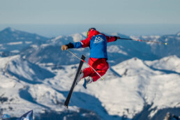 Skifahrer springt über Schanze vor Bergpanorama
